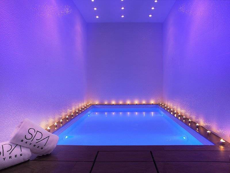 Innenpool des RH Bayren & Spa mit blauer Beleuchtung und brennenden Kerzen