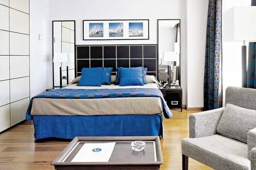 Eurostars Grand Valencia Hotel Schlafzimmer mit Bett, Kissen, Nachttisch und Stuhl.