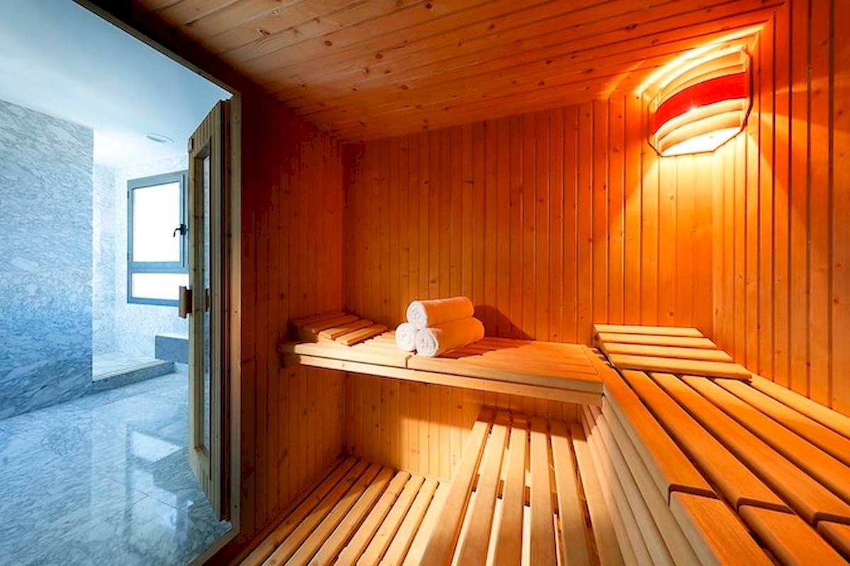 Saunaraum im Eurostars Grand Valencia mit Holzwänden, offenen Bänken und aufgerollten Handtüchern.