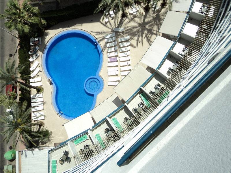 Oberflächenansicht des Schwimmbads im Hotel Principal Affiliated by RH mit weißen Liegestühlen und blauem Wasser.