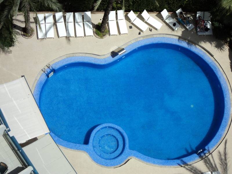 Luftaufnahme des Schwimmbeckens mit weißen Liegen und blauem Wasser im Principal Afilliated by RH.