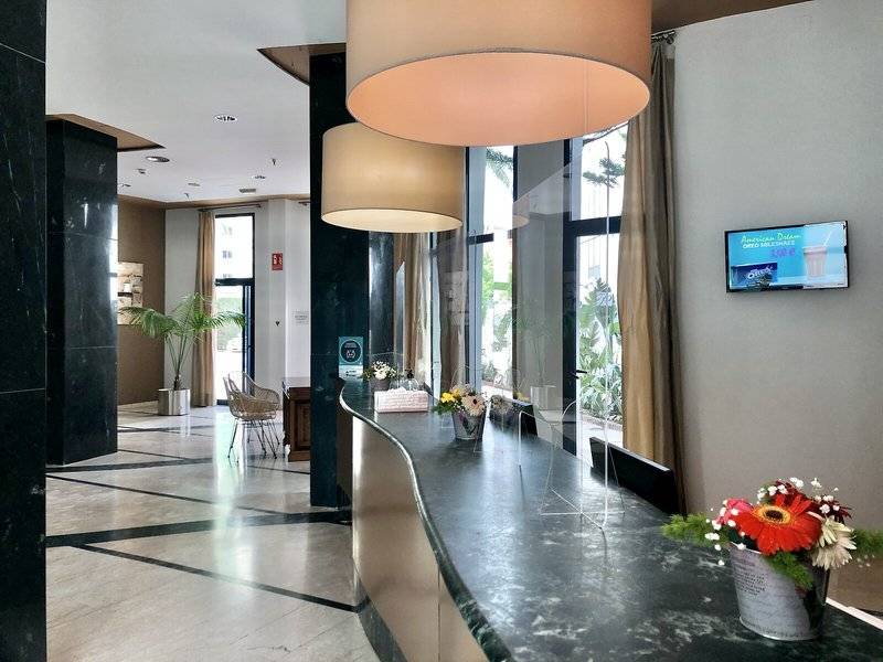 Empfangstresen im Eingangsbereich des Principal Afilliated by RH Hotels mit Blumen und Dekor.