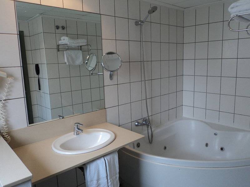 Ein Badezimmer mit Badewanne, Spiegel und Waschbecken im Hotel Principal Afilliated by RH.