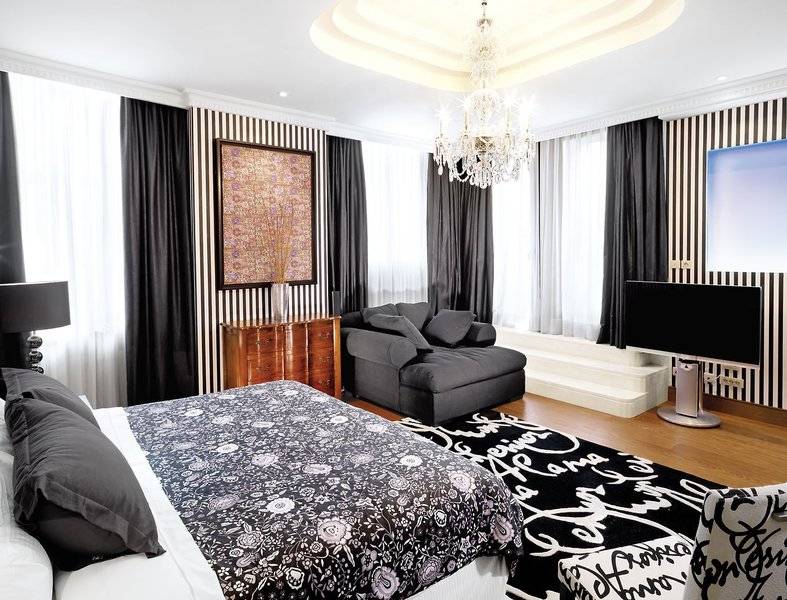 Schlafzimmer im Westin Valencia Hotel mit einem Bett, Sofa, Fernseher, Lampen und Kunstwerk.