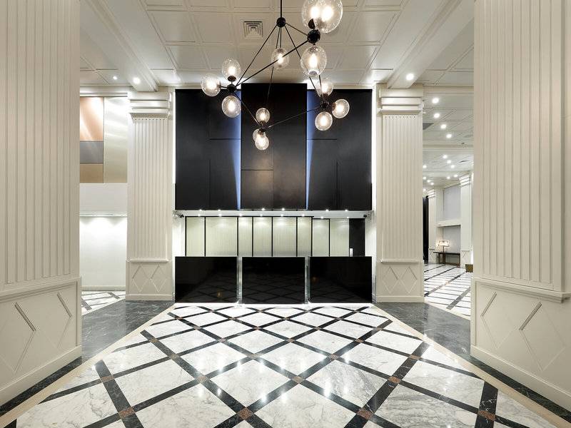 Lobby des Exe Rey Don Jaime Hotels mit schwarzen und weißen Marmorboden und großen Kronleuchter.