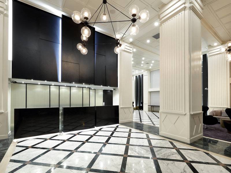 Lobby des Exe Rey Don Jaime Hotels mit schwarzen und weißen Wänden, Marmorboden und Kronleuchter.