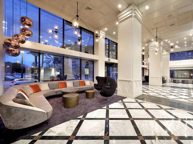 Hotellobby des Exe Rey Don Jaime mit großen Fenstern, einer großen Couch, schwarzen Stühlen und Marmorboden.