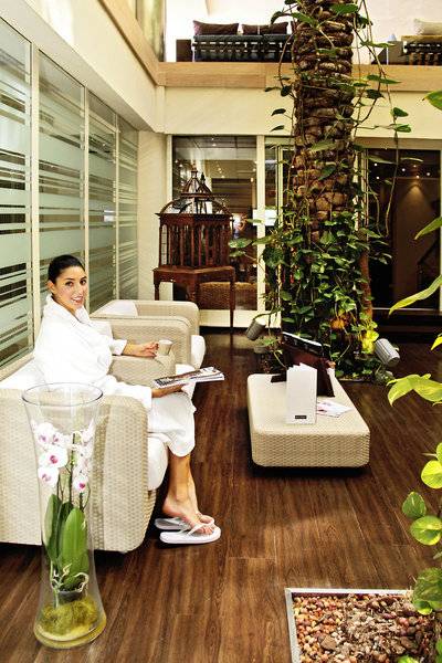 Frau in einem weißen Bademantel sitzt auf einem Stuhl im Wellnessbereich des Almar Timi Ama Resort & Spa