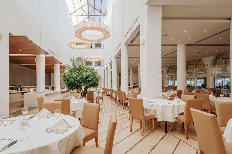 Innenbereich des Lindos Royal Resorts mit gedeckten Tischen und Stühlen, modernes Design.