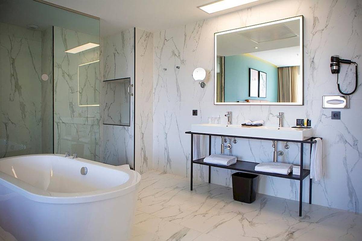 Ein Badezimmer im Riu Plaza Espana Hotel mit Badewanne, Waschbecken und Spiegel.