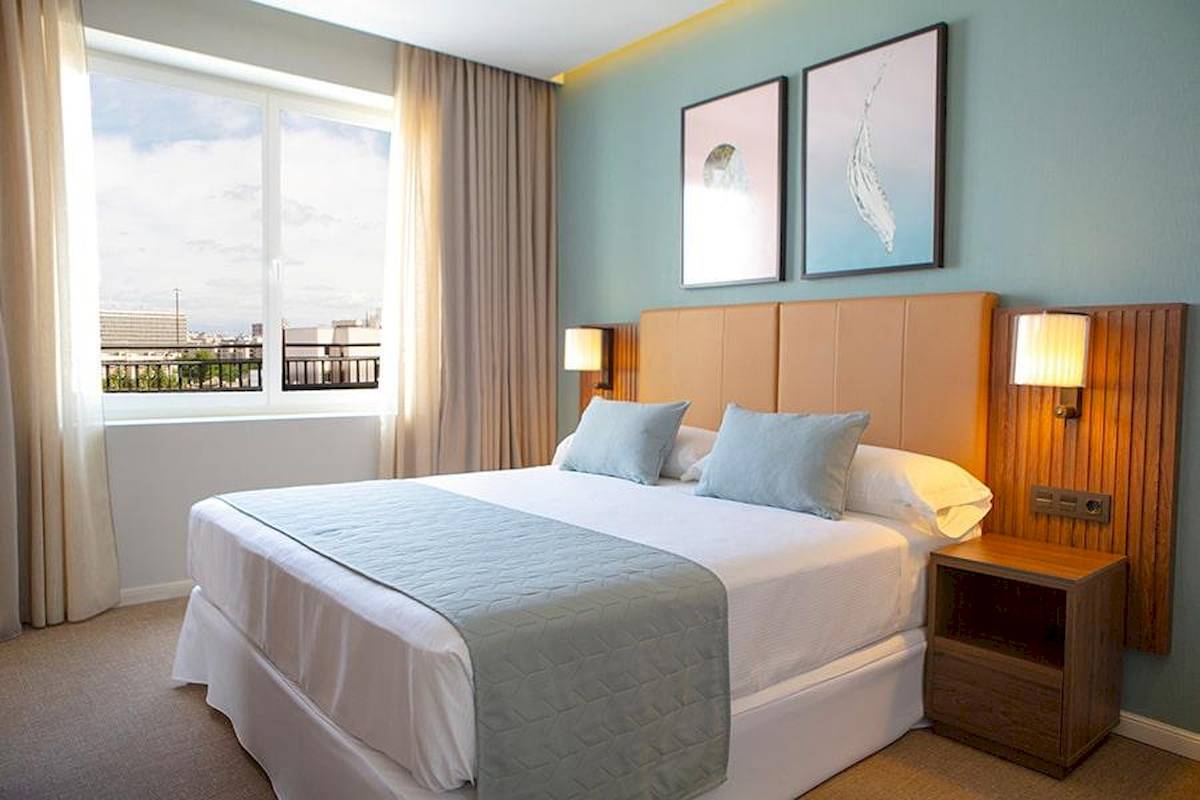 Hotelzimmer mit Bett, Kissen, Fenster und Nachttisch im Riu Plaza Espana