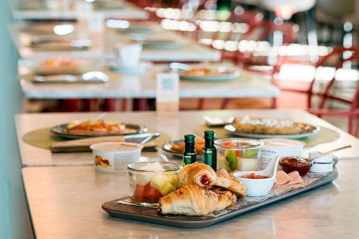 Frühstücksbuffet im Riu Plaza Espana mit Croissants, Obst, und Getränken auf einem Tisch.