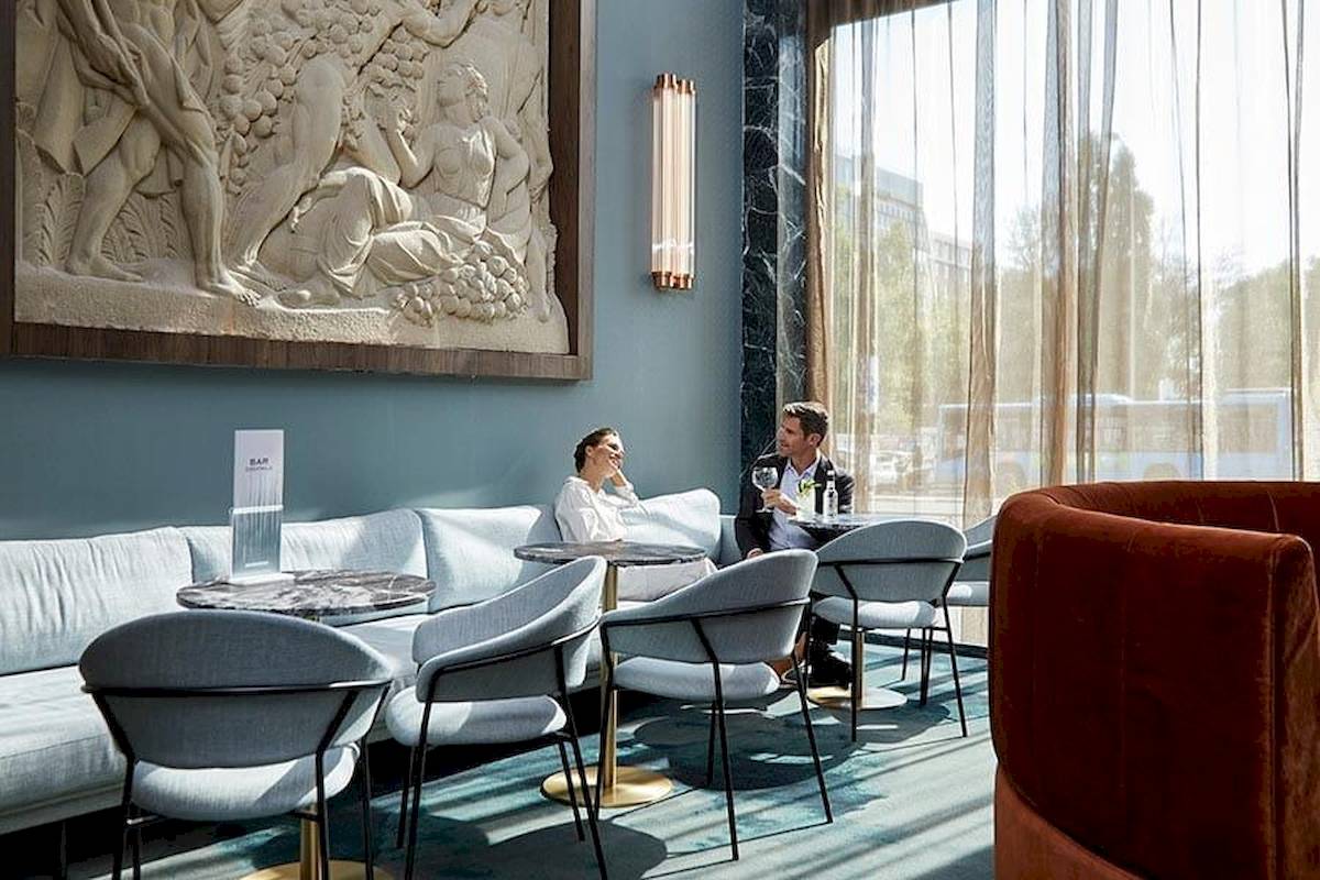 Im Riu Plaza Espana Hotel sitzt ein Paar in einem eleganten Innenraum neben einer Couch.
