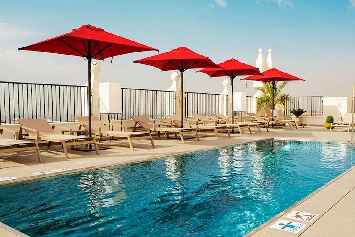 Pool-Terrasse des Riu Plaza Espana Hotels mit roten Sonnenschirmen und Liegen.