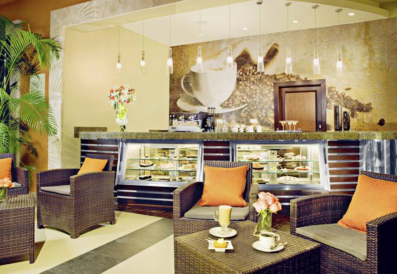 Innenansicht des Cafés im Secrets St. James Hotel mit Möbeln und Dekoration.