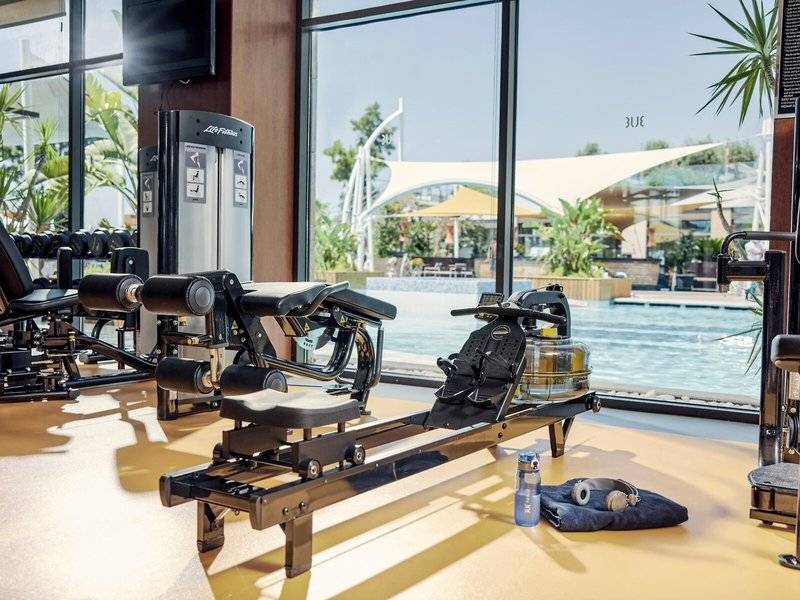 Fitnessstudio im Hotel TUI BLUE Side mit Blick auf den Pool und Trainingsgeräten.