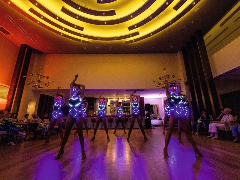 Tänzerinnen im TUI BLUE Side Hotel mit LED-Kleidung und violetten Lichteffekten.