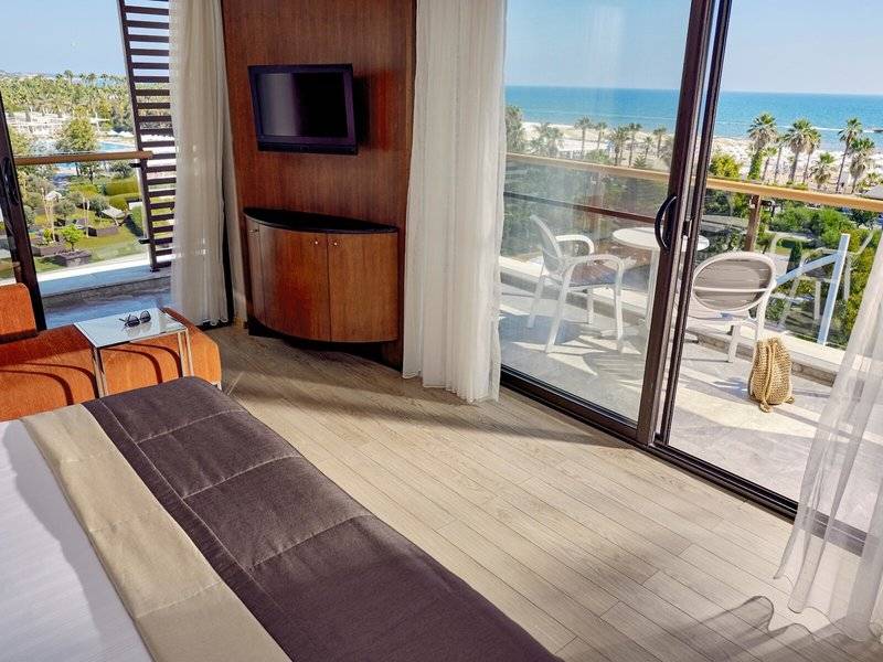 Zimmer im TUI BLUE Side Hotel mit Blick auf das Meer und eine Terrasse mit Möbeln.