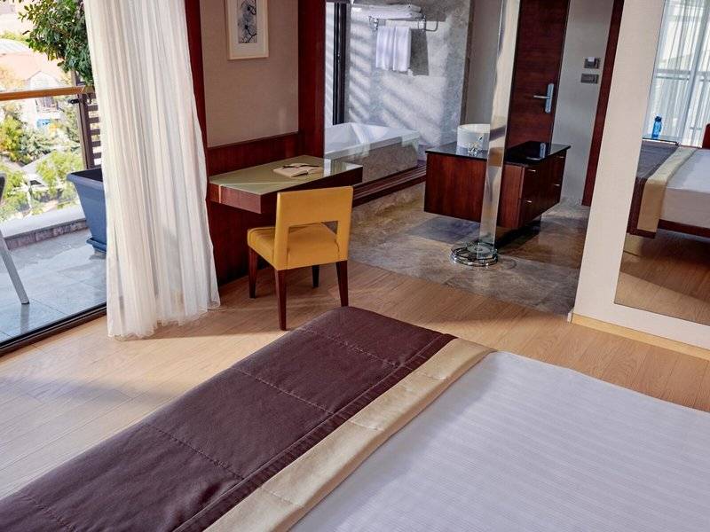 Hotelzimmer im TUI BLUE Side mit Schreibtisch, Sessel, Bad und Balkon.