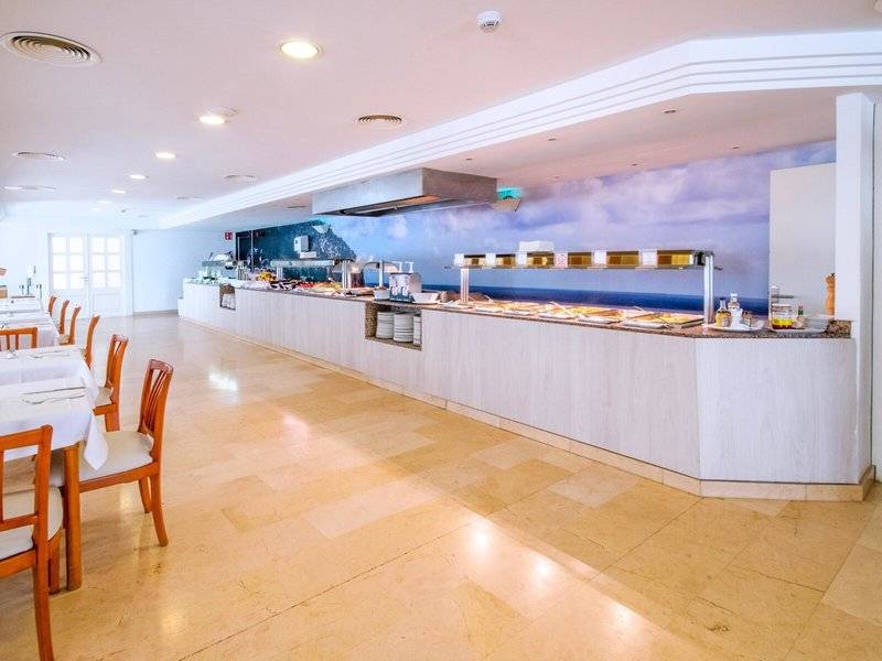 Innenansicht des Restaurants im Canyamel Classic Hotel mit Tisch, Stühlen und Buffet.