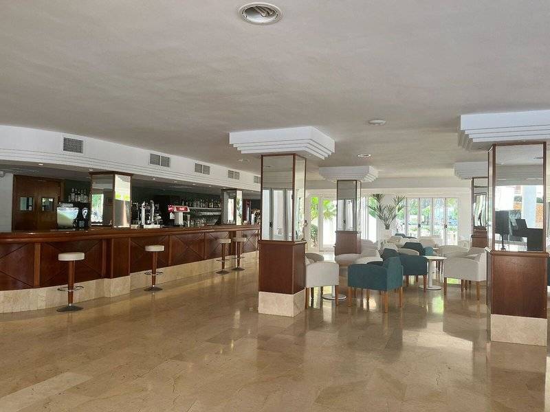 Innenansicht der Bar im Canyamel Classic Hotel mit Theke, Stühlen und Tischen.