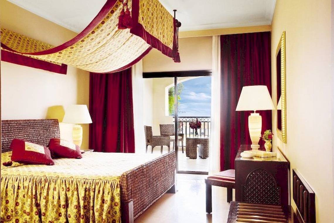 Ein Hotelzimmer mit einem Bett, einem Balkon und verschiedenen Dekorationen.