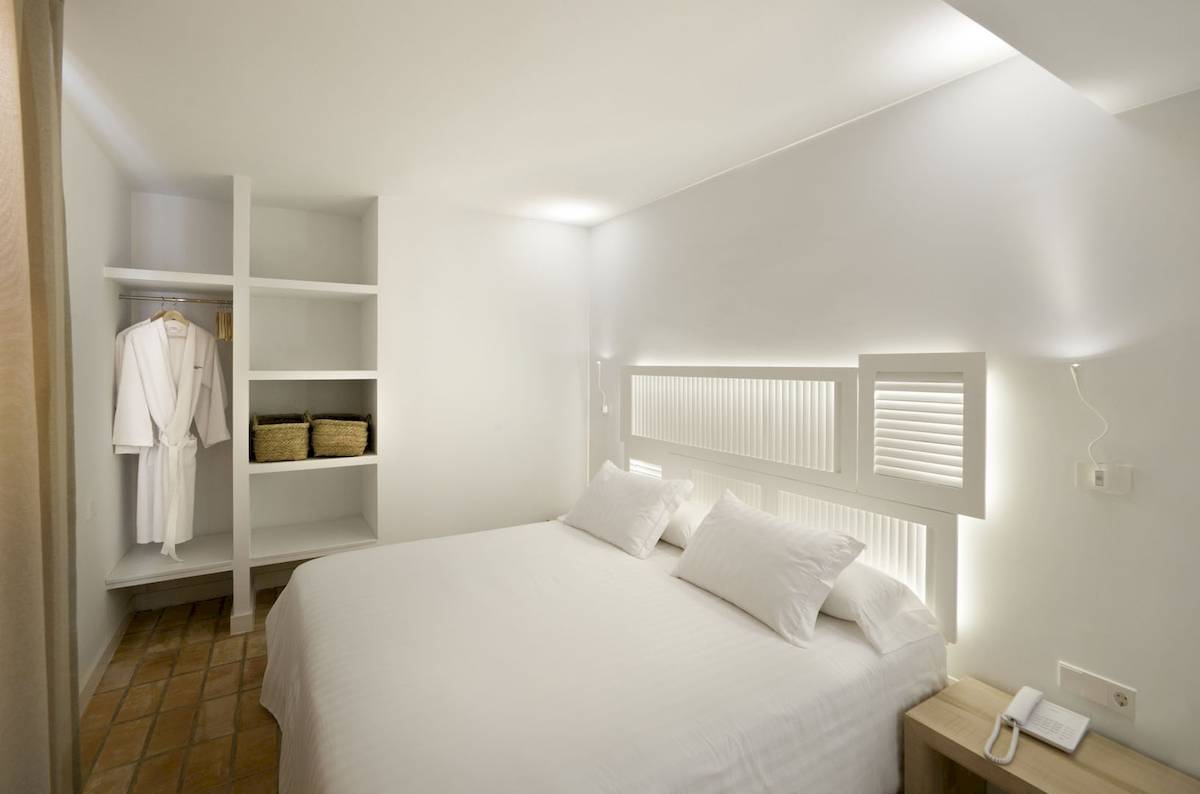 Schlafzimmer im Paraiso de los Pinos Hotel mit weißem Bett, Kissen und Kleiderschrank.