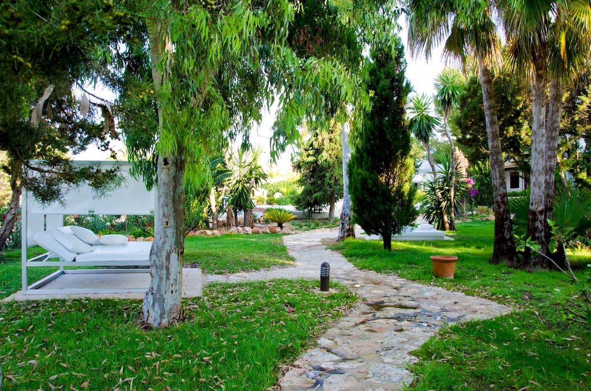 Gartenlounge des Paraiso de los Pinos Hotels mit weißen Möbeln und einem Pfad