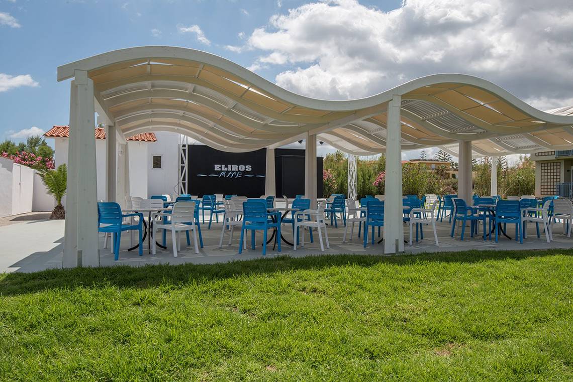Foto der Terrasse des Eliros Mare Hotels mit blauen und weißen Stühlen und Tischen.