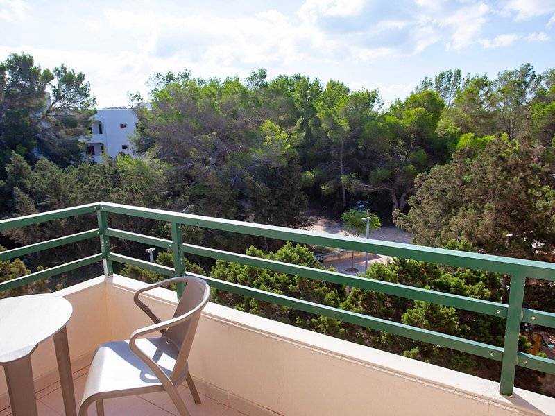 Balkon des Rosales Formentera Hotels mit Tisch, Stühlen und Blick auf eine bewaldete Landschaft