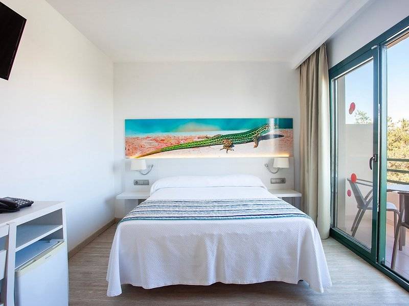 Rosales Formentera Hotelzimmer mit Bett, Fernseher und Balkonzugang.
