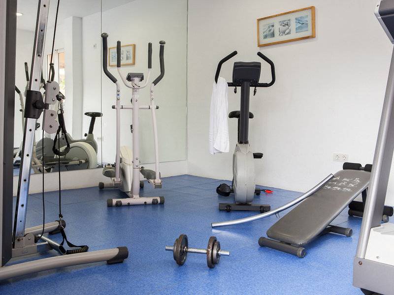 Fitnessraum im Hotel Voramar Formentera mit verschiedenen Trainingsgeräten und blauem Boden.