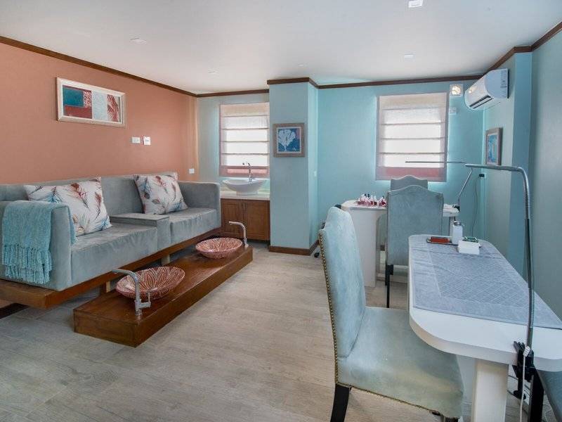 Innenbereich des Spa-Behandlungsraums im Hotel The Sands Barbados mit Sofa, Schreibtisch und Waschbecken.
