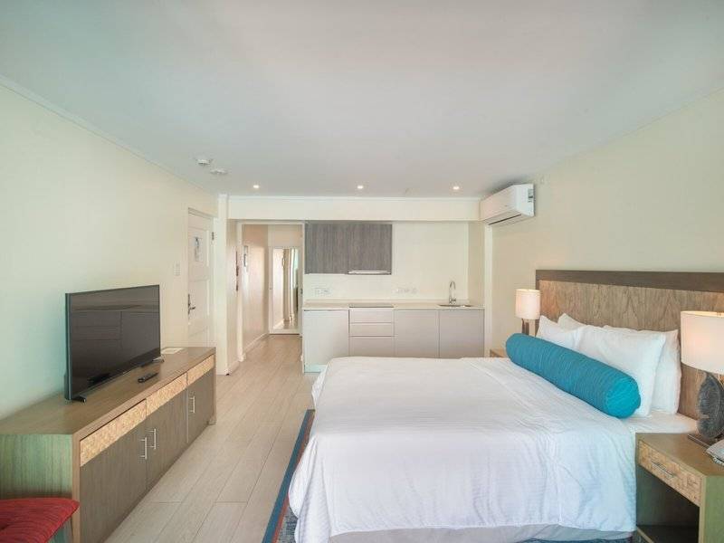 Schlafzimmer im The Sands Barbados Hotel mit großem Bett, Fernseher und Küche