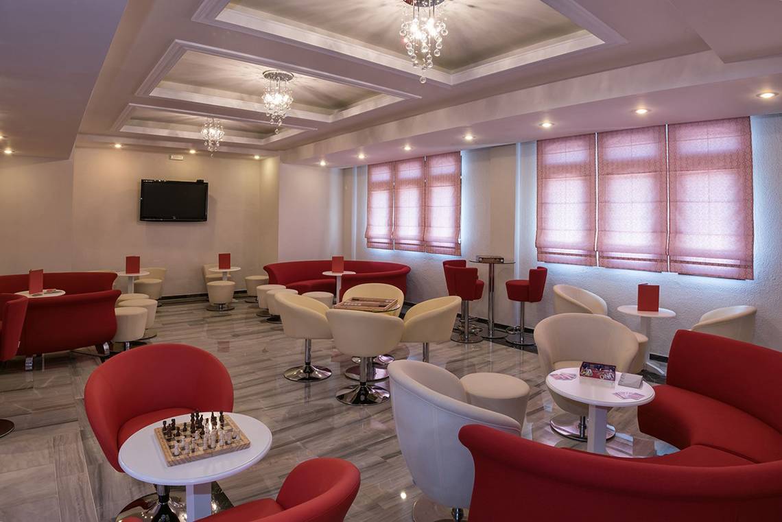 Lobby-Bereich des Eliros Mare Hotels mit Sitzmöbeln und Spieltischen.