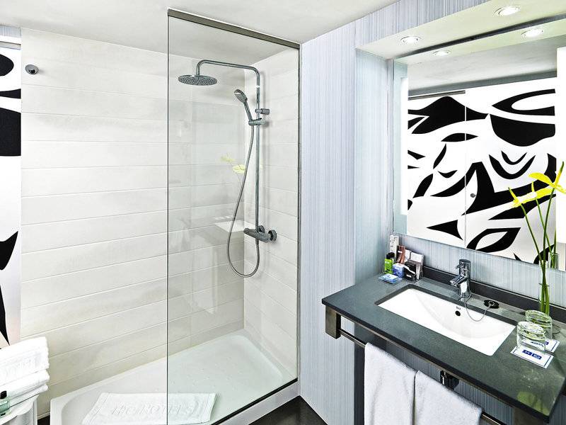 Badezimmer im H10 Tenerife Playa Hotel mit Glasdusche, Waschbecken und großer Spiegel.