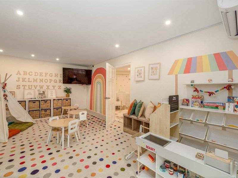 Ein buntes Kinderzimmer im Sugar Bay Barbados Hotel mit Tisch, Stühlen und einem Teppich mit bunten Punkten.