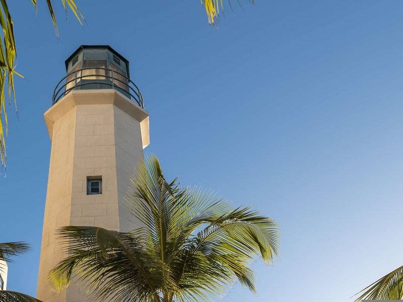 Leuchtturm des Hilton Barbados Hotels mit blauem Himmel und Palmen im Vordergrund