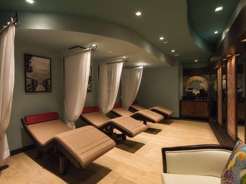 Spa-Lounge-Bereich im Hilton Barbados mit mehreren Behandlungsliegen und weißen Vorhängen.
