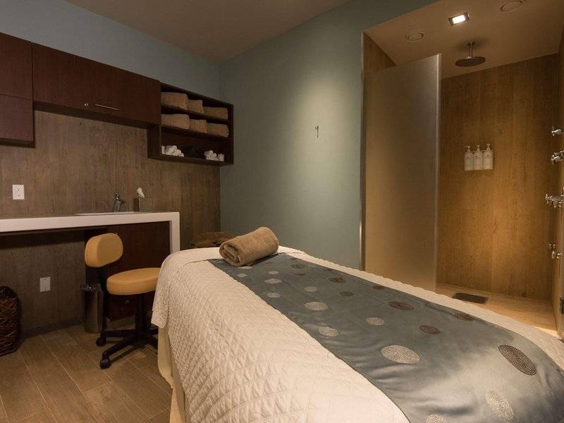 Massagebehandlungsraum im Hilton Barbados Hotel mit einem Bett, einem Stuhl und einer Dusche.