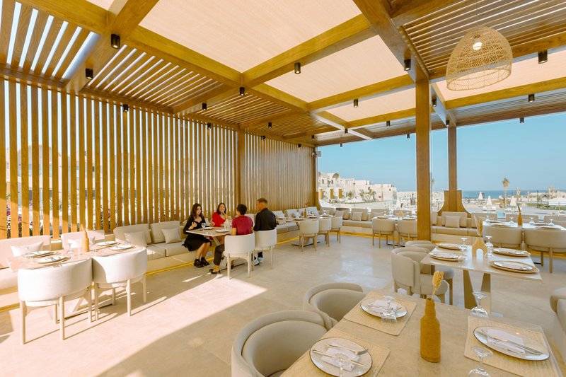 Innenbereich eines Restaurants im Sunrise Anjum Resort mit Gästen an Tischen und Blick auf das Meer.