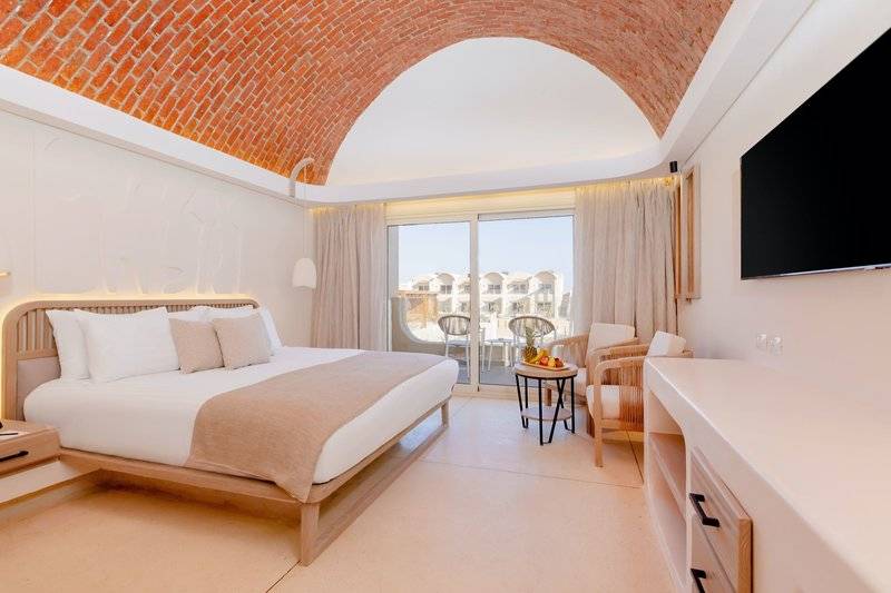 Schlafzimmer im Sunrise Anjum Resort mit einem Bett, Balkon, Fernseher und Möbeln.