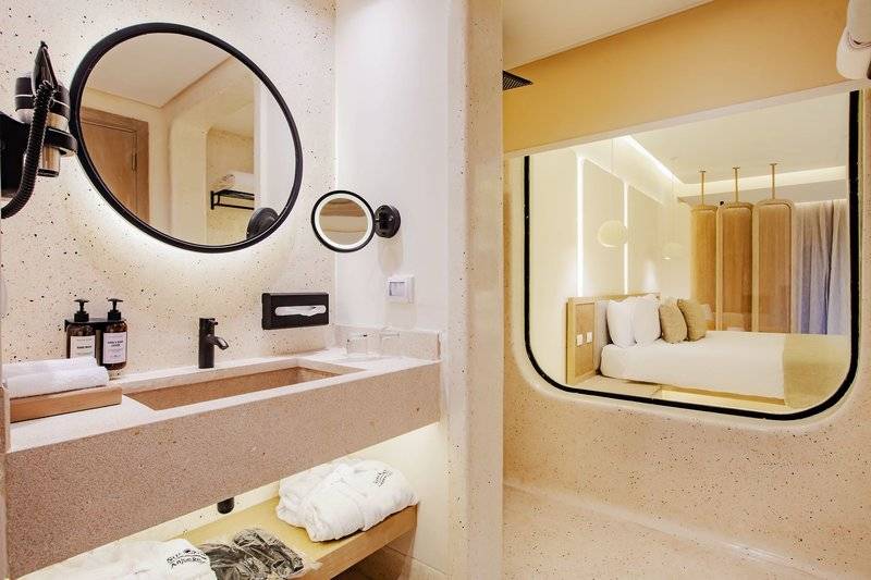 Badezimmer im Sunrise Anjum Resort mit modernem Design, großer Dusche und Blick auf das Bett.