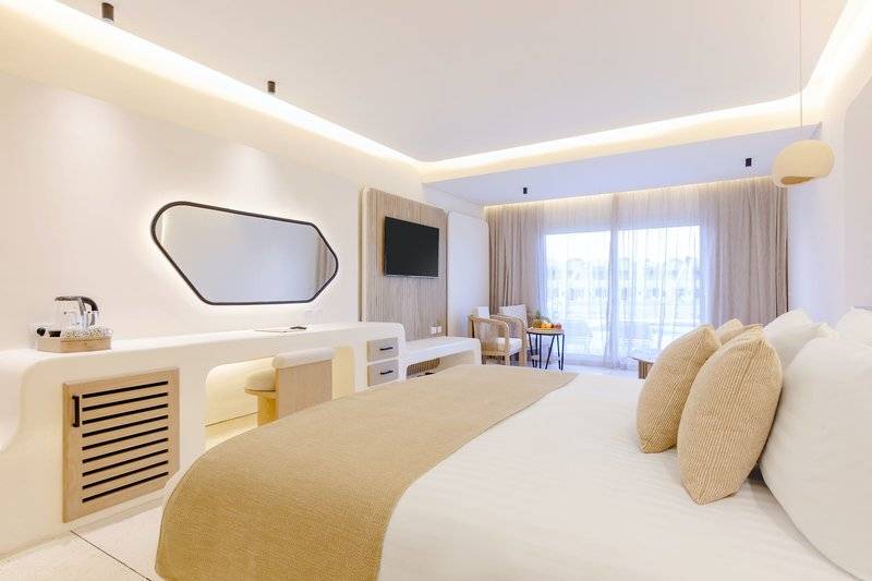 Ein modernes Hotelzimmer im Sunrise Anjum Resort mit einem großen Bett, weißen Wänden und einem Fernseher.