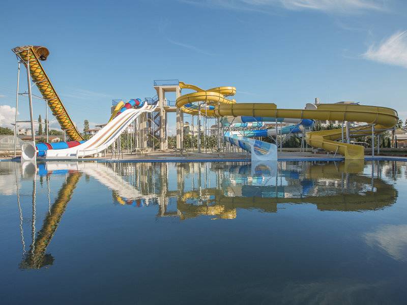 Wasserrutschen im Freizeitpark mit blauem Himmel und reflektiertem Wasser