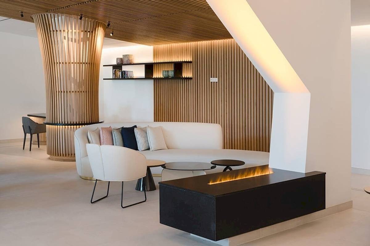 Innenbereich des Plus Fariones Suite Hotels mit weißem Sofa, schwarzem Kamin und Holzelementen.