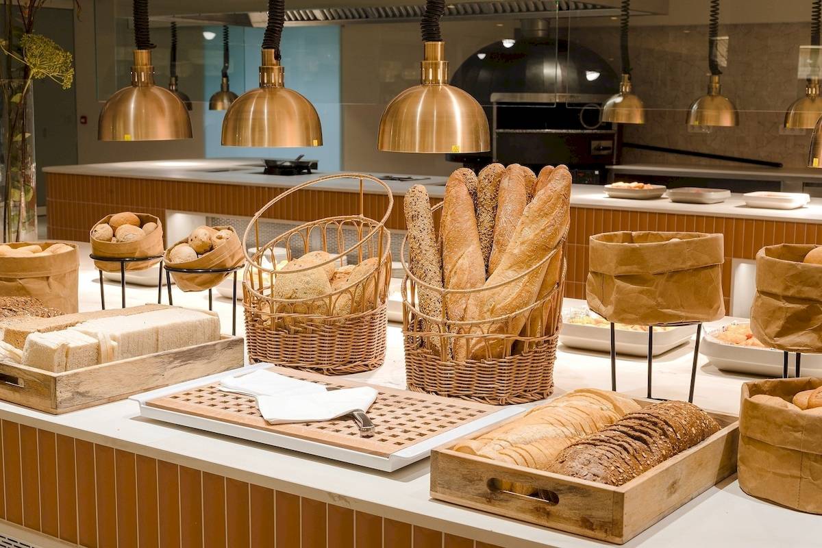 Frühstücksbuffet im Plus Fariones Suite Hotel mit verschiedenen Brotsorten, Brötchen und anderen Gebäck.