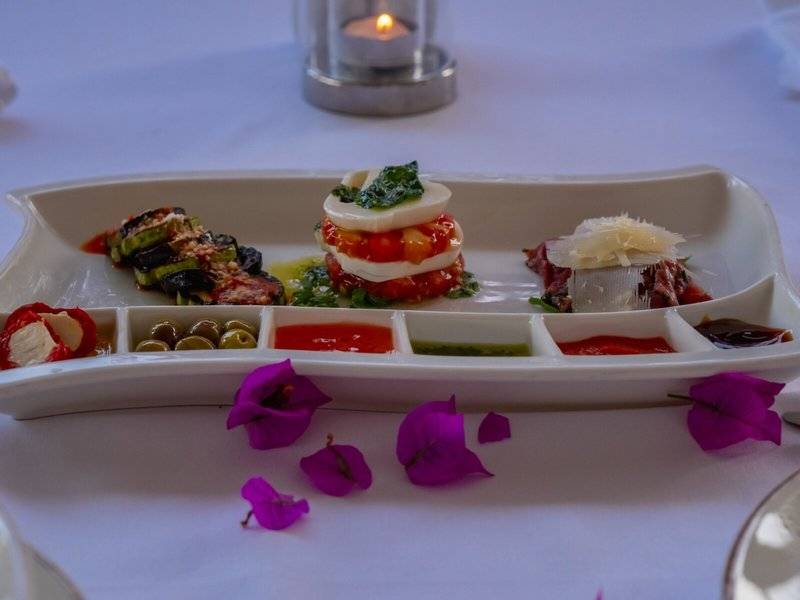 Eine Speiseplatte mit verschiedenen Toppings und Saucen, serviert im Ducale Lara Hotel.