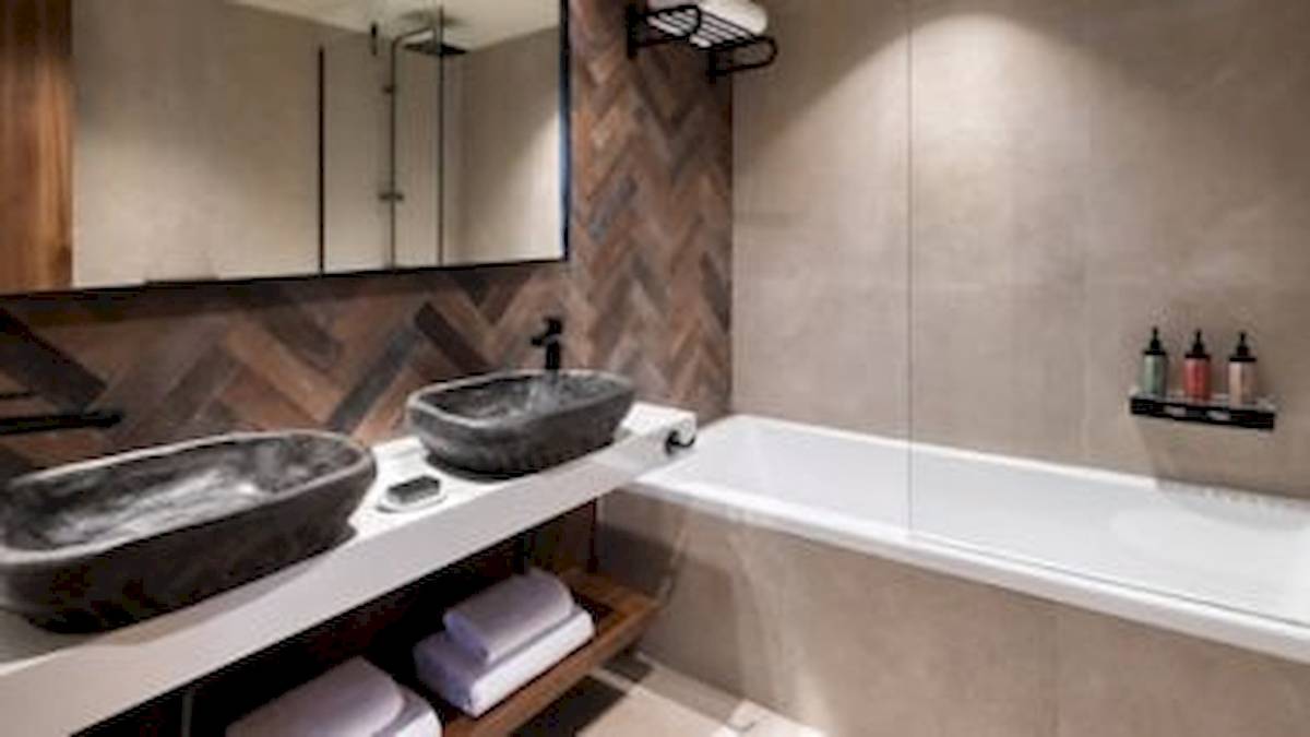 Ein Badezimmer mit zwei Waschbecken, einer Badewanne und einer Dusche im Domes Aulus Zante Hotel.