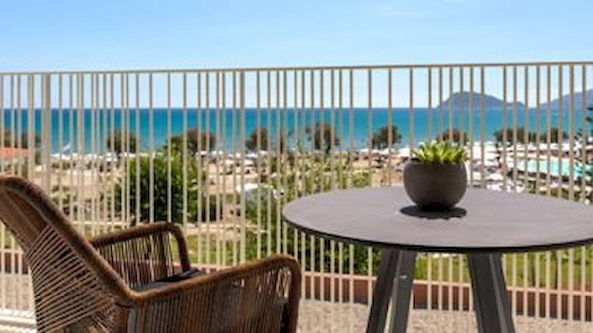 Ein Balkon mit Tisch und Stuhl bietet Aussicht auf das Meer und eine Bergkette.